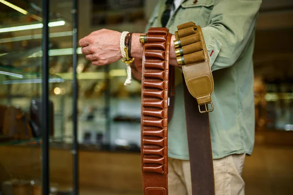 Male hunter buying leather bandolier in gun store — Stock fotografie