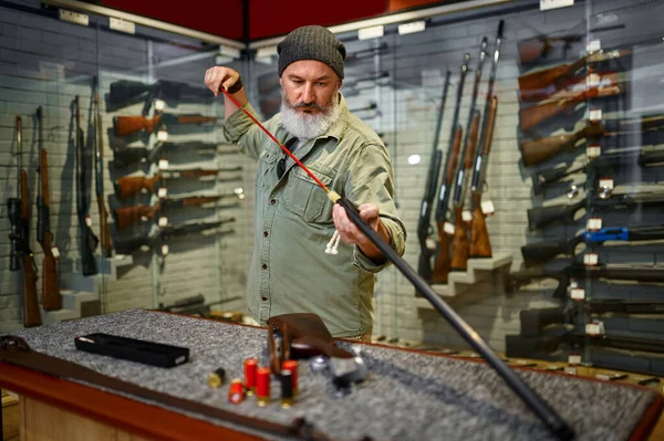 Cazador de hombres barbudos eligiendo baqueta en la tienda de armas —  Fotos de Stock