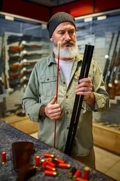 Sakallı erkek avcı silah dükkanında ramrod seçiyor. — Stok fotoğraf