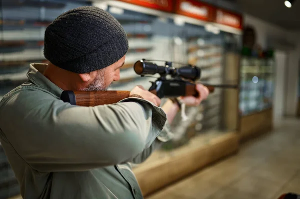 Hunter kupuje pušku s optickým zaměřovačem, obchod se zbraněmi — Stock fotografie