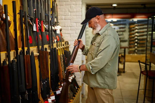 Hunter at showcase with hunting rifles, gun store — Foto de Stock