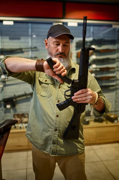 Man loads automatic rifle in gun store — Stock fotografie