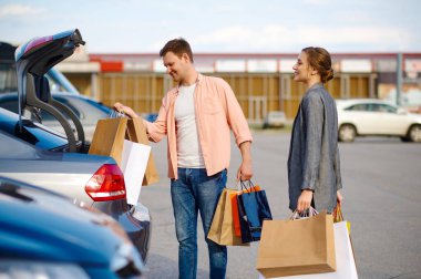 Couple puts their purchases in trunk on parking