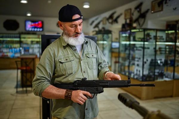 Man säljaren håller automatgevär i vapenaffär — Stockfoto