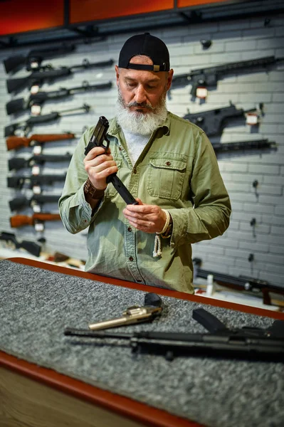 Hombre recarga pistola en el mostrador en la tienda de armas —  Fotos de Stock