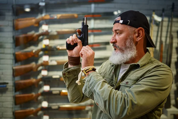 El hombre barbudo mueve el perno de la pistola en la tienda de armas —  Fotos de Stock