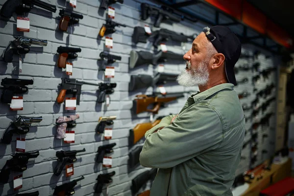 銃店のショーケースでピストルを選ぶ男 — ストック写真