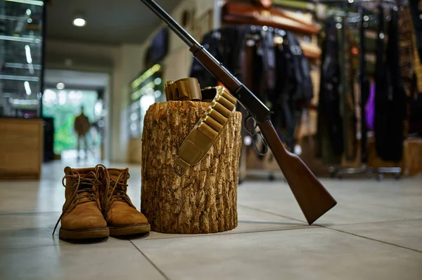 Rifle and hunting boots at the stump in gun store — Stock Photo, Image