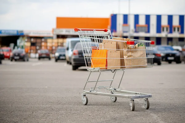 Winkelwagen met kartonnen tassen op supermarkt parkeerplaats — Stockfoto