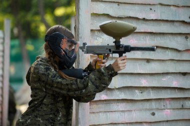 Paintball savaşçısı sığınaktan silahla ateş eder.