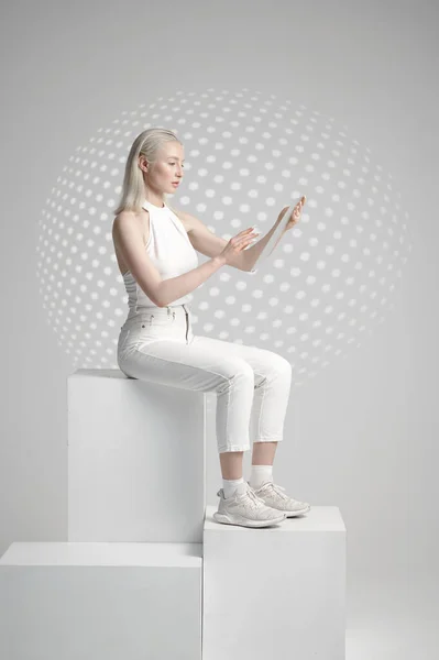 Futuristic young woman sitting on cube —  Fotos de Stock