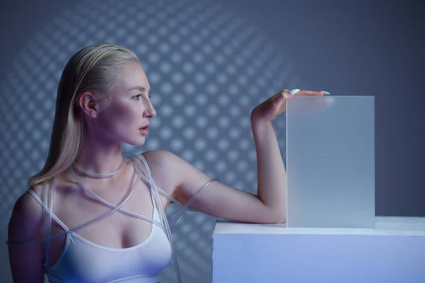 Futuristic young woman near blur glass on cube — Zdjęcie stockowe