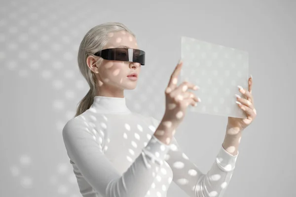 Young woman in glasses holds futuristic gadget Stock Picture