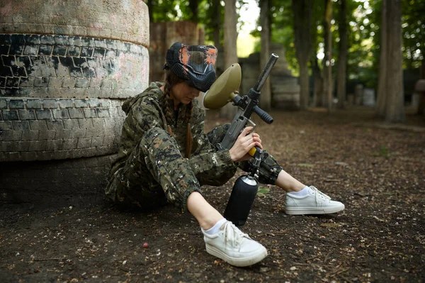 Female paintball player sitting on the ground — Stockfoto