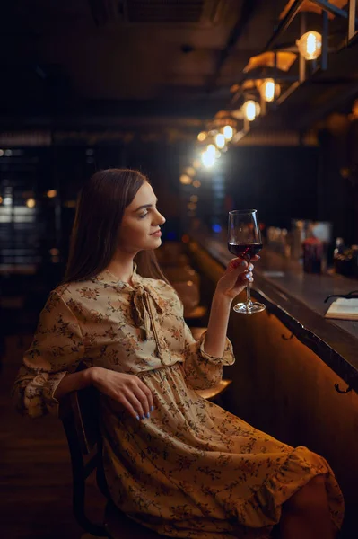 Mulher sozinha com copo de vinho sentada no bar — Fotografia de Stock