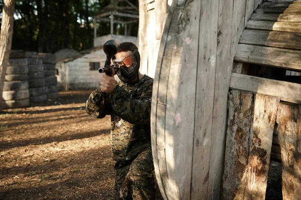 ペイントボールプレーヤーは避難所から銃で狙います — ストック写真