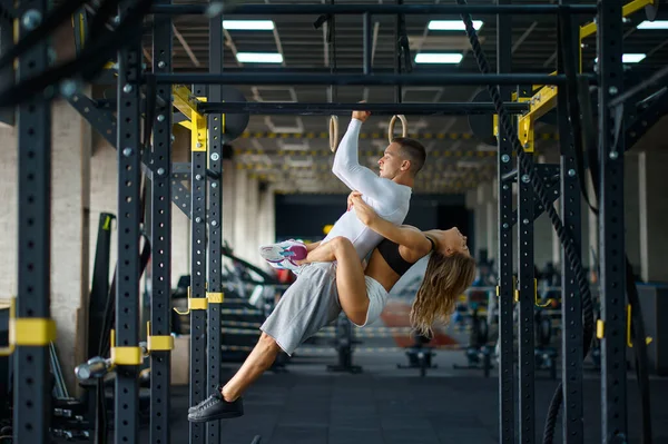 Amore sportivo coppia abbracci su barra orizzontale in palestra — Foto Stock