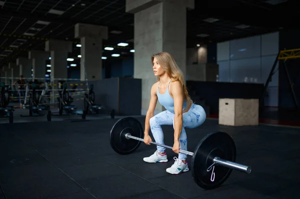 Sexy vrouw doet oefening met lange halter in de sportschool — Stockfoto