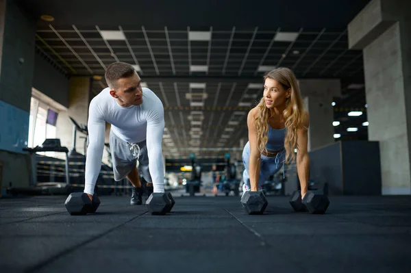 Couple faisant push-ups avec haltères dans la salle de gym — Photo