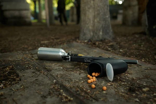 Paintball gun and marker balls on ground closeup — Stock Photo, Image