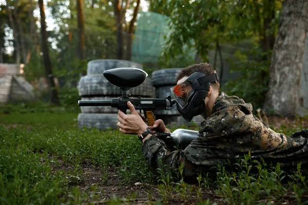 Paintball wojownik strzela leżąc na trawie — Zdjęcie stockowe