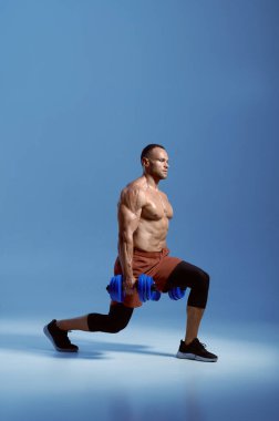 Dambılı erkek sporcu, stüdyoda eğitim görüyor.