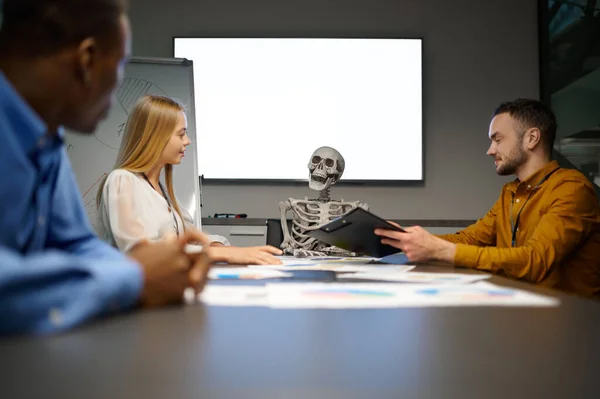 Equipo de gerentes y esqueleto en la oficina de TI, broma — Foto de Stock