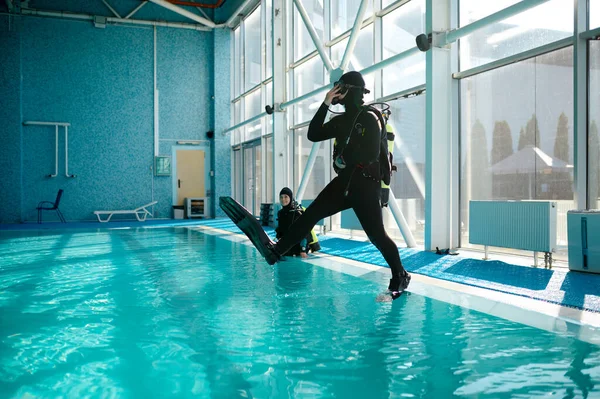 Duiker in duikuitrusting springt in het zwembad, duiken — Stockfoto