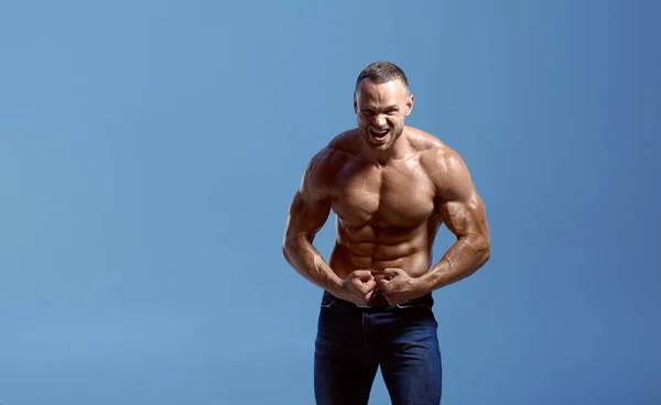 Idrottare med muskulös kropp visar biceps i studio — Stockfoto