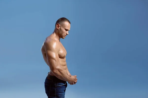 Atleta masculino mostra seus bíceps em estúdio, vista lateral — Fotografia de Stock