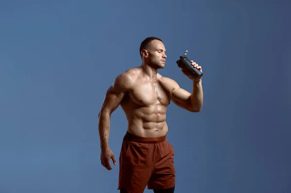 Atleta masculino muscular bebe água em estúdio — Fotografia de Stock