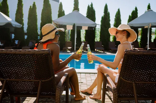 Freundinnen trinken Bier auf Sonnenliegen am Pool — Stockfoto
