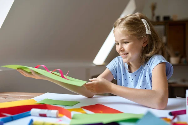 Weibliches Kind klebt buntes Papier am Tisch — Stockfoto