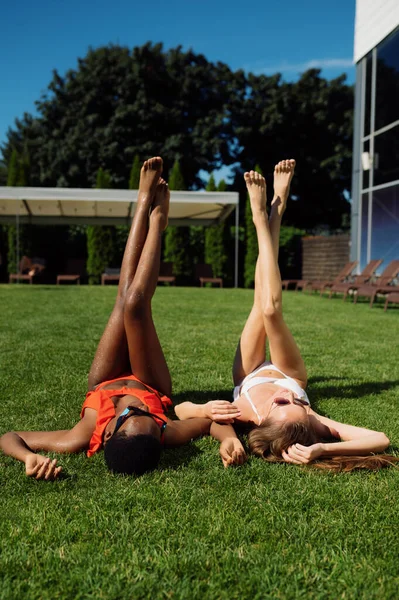 Zwei Freundinnen ruhen sich im Gras am Pool aus — Stockfoto