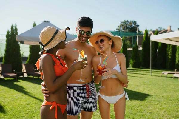 Vrienden met cocktails poseren bij het zwembad in hotel — Stockfoto