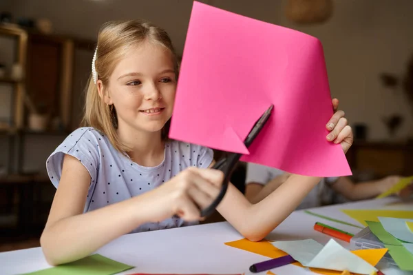 Little girl cuts colored paper, kid in workshop — Stock Photo, Image