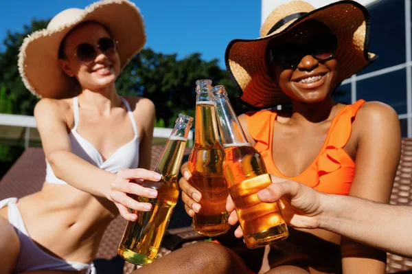 Vänner clink flaskor med öl nära poolen — Stockfoto