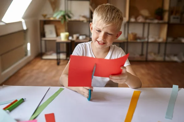 Kleine jongen snijdt gekleurd papier, kinderen in workshop — Stockfoto