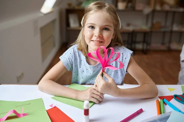 Weibliches Kind klebt buntes Papier am Tisch — Stockfoto