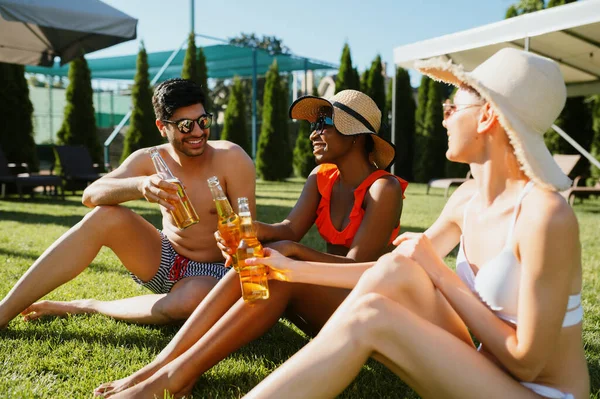 Веселі друзі п'ють пиво біля басейну — стокове фото