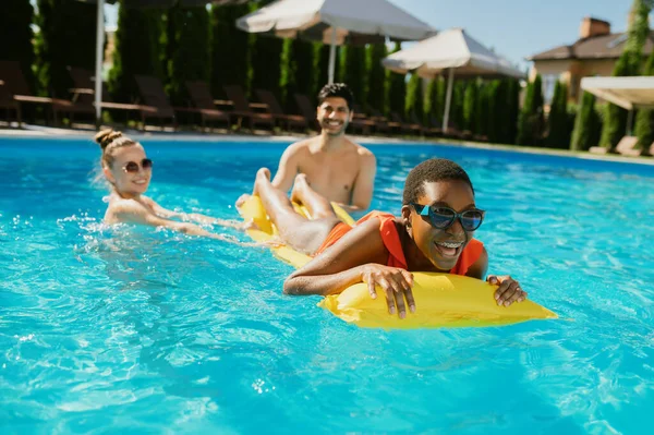 Alegre amigos nadan en un colchón en la piscina — Foto de Stock