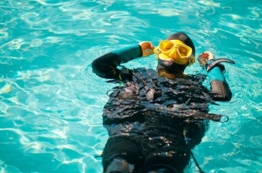 Dalış ekipmanlı kadın dalgıç havuzda poz veriyor, üst manzara