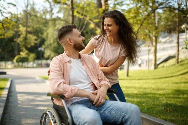 Fiatal pár tolószékkel sétál a parkban — Stock Fotó