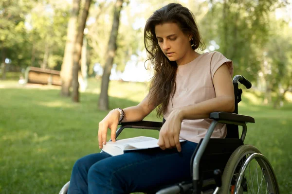 Mozgássérült nő kerekesszékes olvasókönyv a parkban — Stock Fotó