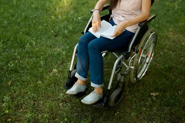 Behinderte Frau im Rollstuhl liest Buch im Park — Stockfoto