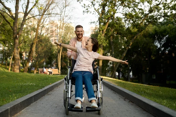 Vidám szerelmespár kerekesszékes sétával a parkban — Stock Fotó