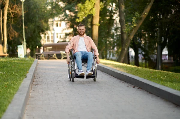 Gehbehinderter Mann im Rollstuhl fährt auf Gehweg im Park — Stockfoto