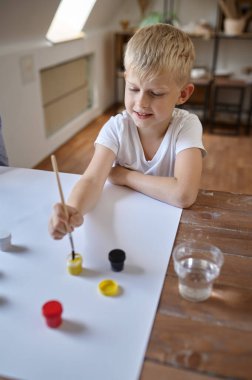 Küçük çocuk gouache çiziyor, çocuklar atölyede.
