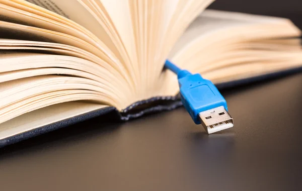 USB-kabeln sticker ut från en bok — Stockfoto