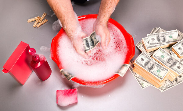 Human is washing dollars banknotes in foam
